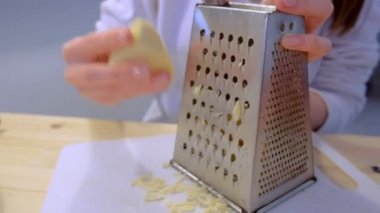 Kadın peynir rende evde mutfakta üzerinde losyonları. Eller yakın çekim.