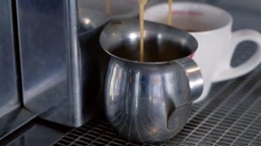 Espresso kahve makinesinden sürahi ve fincan döker.