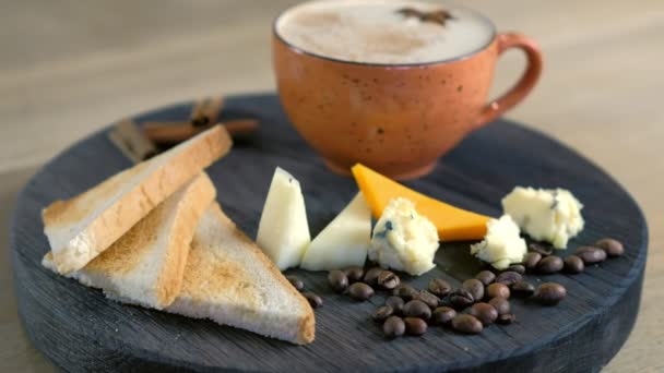 Kaas koffie met gesmolten kaas, stukjes kaas en brood toast op een WOD zwarte tray. Close-up zijaanzicht. — Stockvideo
