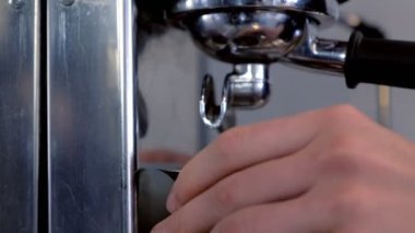 Barista sürahi ve bardak taze espresso kahve makinesi üzerinden dökülen. Eller yakın çekim.