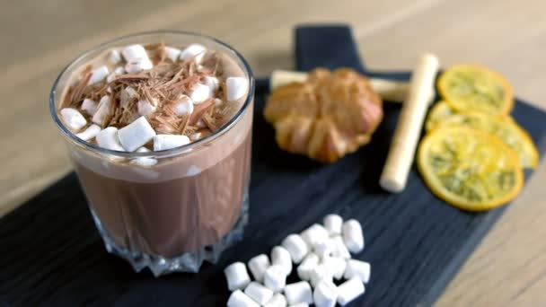 Kakao mit Marshmallow im Steinglas auf einem schwarzen Holzblech mit Kuchen und Zitrone. Seitenansicht aus nächster Nähe. — Stockvideo