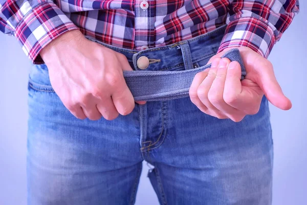 Mann legt schnell den Gürtel ab und schlägt ihn auf die Hand, Hände in Großaufnahme. — Stockfoto