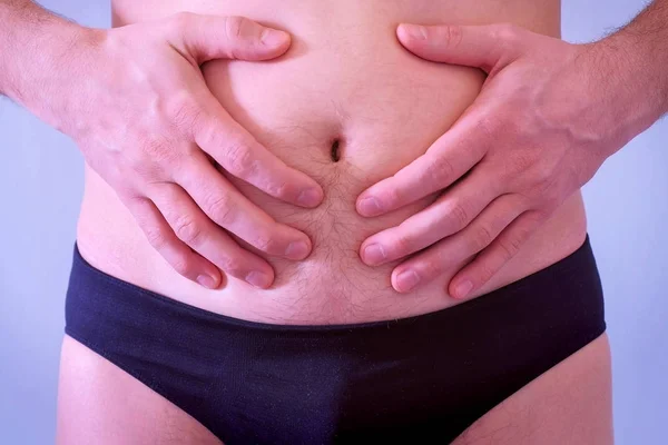 Hombre en calzoncillos toca su flácido y gordo estómago desnudo, vista de cerca . — Foto de Stock