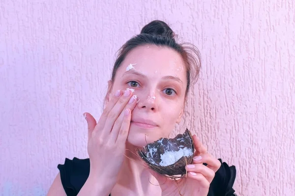 Mujer está aplicando mascarilla de coco casera fresca en la cara de la cáscara de coco . —  Fotos de Stock