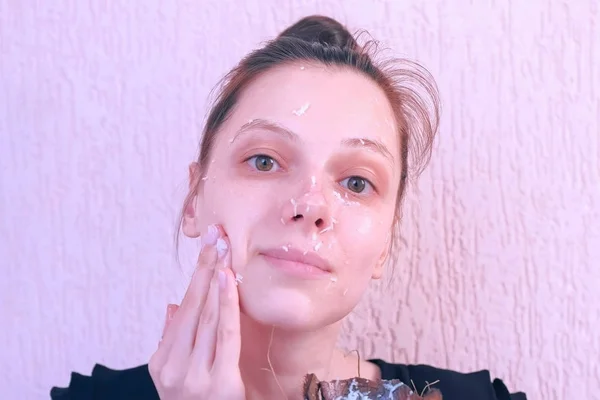 Woman is applying fresh homemade coconut scrub on the face from coconut shell. — Stock Photo, Image