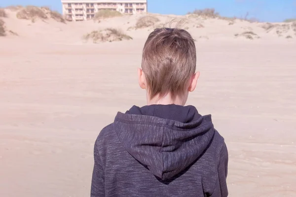 Παιδί αγόρι είναι περπάτημα στην αμμώδη παραλία για να αμμοθίνες πίσω θέα εξωτερικές δραστηριότητες. — Φωτογραφία Αρχείου