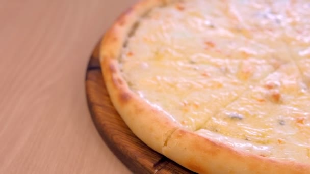La mitad de la pizza en rodajas con diferentes tipos de queso en la tabla de madera vista de cerca . — Vídeos de Stock