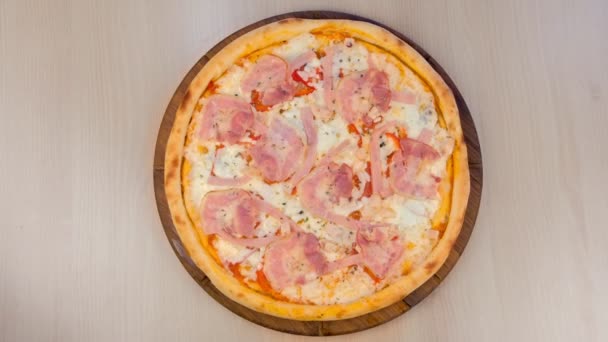 Pizza met spek en kaas op houten bord op de tafel. Close-up bovenaanzicht. — Stockvideo