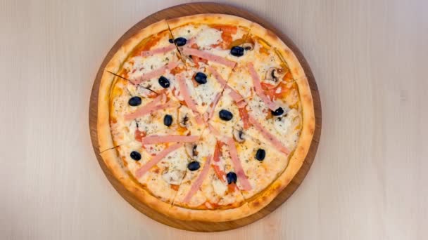 Het snijden van pizza met ham en kaas op houten bord op tafel. Close-up weergave. — Stockvideo