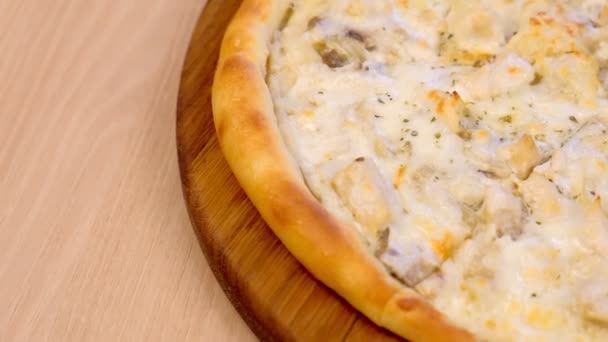 Metade de fatiar pizza com champinhons de cogumelos e queijo em tábua de madeira na mesa. Vista lateral em close-up . — Vídeo de Stock