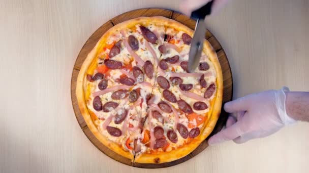 Cook cuts pizza with smoked sausage, ham and cheese. Close-up top view. — Stock Video