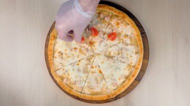 Şef tavuk ve peynir ahşap tahta üzerinde pizza domates ve marul koyar. Eller yakın çekim.