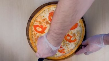 Şef, domates ve peynirli pizzayı tahta tahtada dilimler halinde keser. Üst te. Eller yakın çekim.