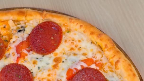 Quater of slicing salami pizza on wooden board on the table. Close-up top view. — Stock Video