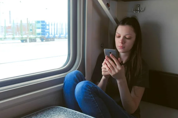 ट्रेनमध्ये थकलेला तरुण स्त्री मोबाइल फोनमध्ये व्हिडिओ पाहणे . — स्टॉक फोटो, इमेज