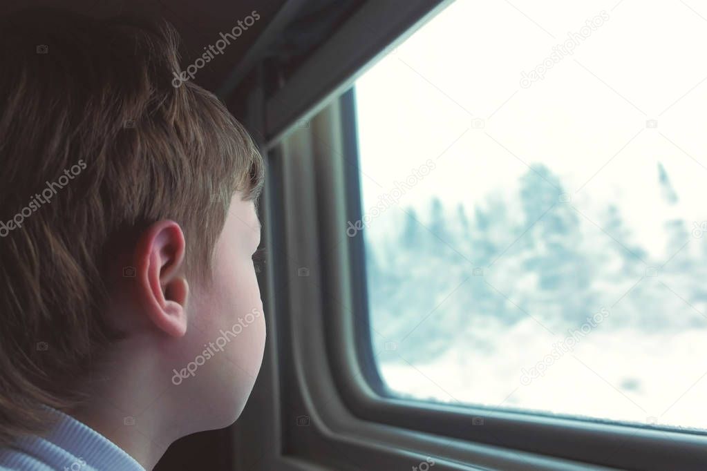 Boy is looking in window in moving train on winter landscape.