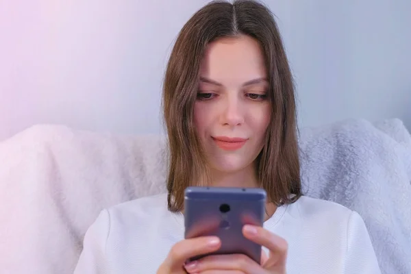 Mujer morena joven está leyendo un libro en el teléfono móvil . — Foto de Stock