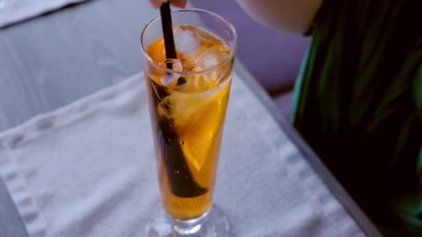 Vrouw mengt alcohol cocktail met stro op de champagne fluit met sinaasappel en drinkt het, handen close-up. — Stockvideo