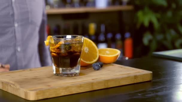 Bartendern sätter alkohol cocktail på stenar glaset till klienten i bardisk. Händer närbild. — Stockvideo