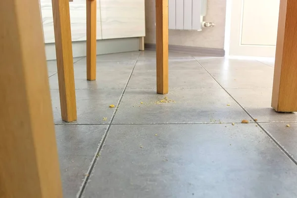 テーブル下の床にパン粉。クローズ アップ ビュー。台所の床の汚れ. — ストック写真