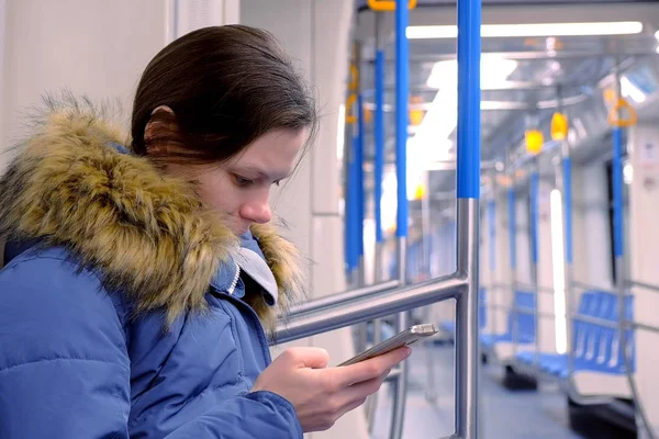 थकलेल्या महिलेचे पोर्ट्रेट रिक्त सबवे कारमध्ये चालते आणि तिच्या स्मार्टफोनवर ब्राउझिंग करते. बाजूला दृश्य . — स्टॉक फोटो, इमेज