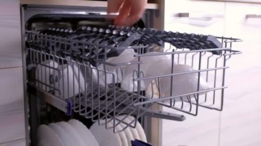 Mans el beyaz bardak ve cam koyarak ve kirli beyaz bulaşıkları ile bulaşık makinesi kapatıyor.