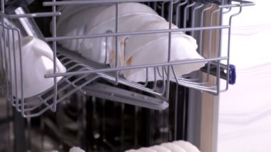 Kirli beyaz bulaşıklar ve çatal bıçak takımı ile bulaşık makinesi sepetleri.