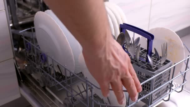 Mans hand is closing dishwasher with dirty white dishes. — Stock Video