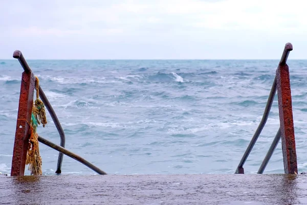 Лестница, ведущая в бурное море. Плохой день на пляже с большими волнами . — стоковое фото