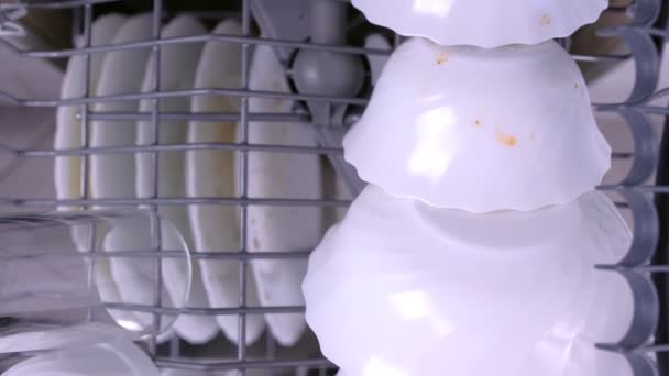 Mans hand puts a white dirty cups in the upper basket of dishwasher and pushes it with kitchenware. — Stock Video