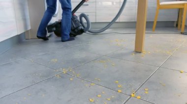 Küçük çocuk mutfak zemini süpürme. O gri çini dağılmış Mısır gevreği kadar tidies. Bacaklar yakın çekim.