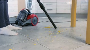 Kadın fırça olmadan gri kiremit ile mutfak zemin süpürme, elektrikli süpürge sadece Boru. Yakın çekim bacaklar.