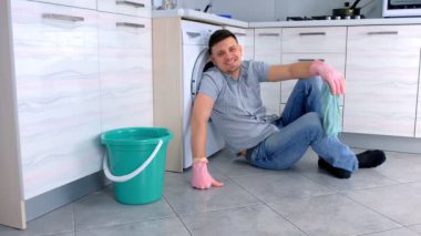 Lastik eldiven mutlu gülümseyen adam mutfak katta oturan temizlik bir dinlenme var.