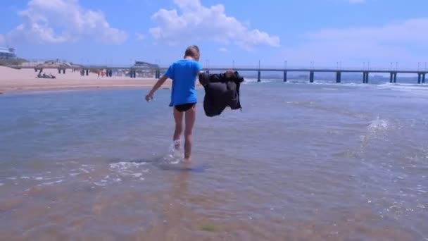 Child boy on sea vacation walks at sea water rest on sandy beach in windy day. — Stock Video