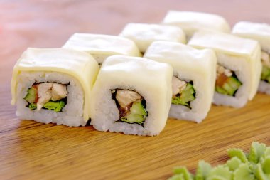 Tavuk, salatalık, yeşil ve krem chesse rulo üstte ahşap tahta sebze ile servis.