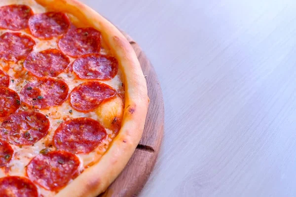 A fele Szalámis pizza fából készült táblán az asztalon. Close-Up Nézd. — Stock Fotó