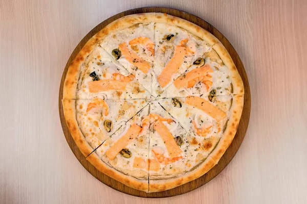 Разрезание пиццы с морепродуктами и сыром на деревянной доске, вид крупным планом . — стоковое фото