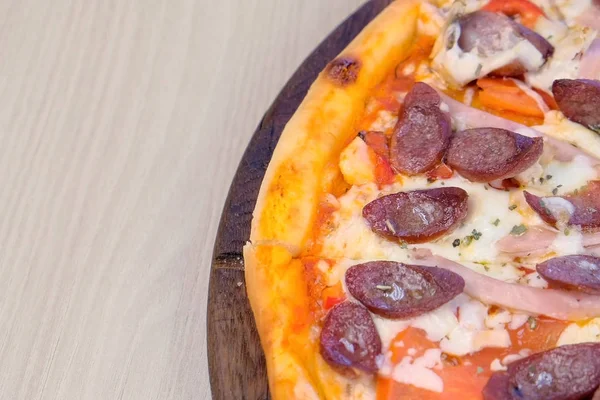 Pizza zur Hälfte mit Räucherwurst, Schinken und Käse. Nahaufnahme von oben. — Stockfoto