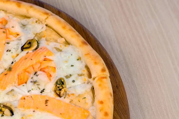 Pizza in Scheiben schneiden mit Meeresfrüchten und Käse auf Holzbrett, Nahsicht. — Stockfoto