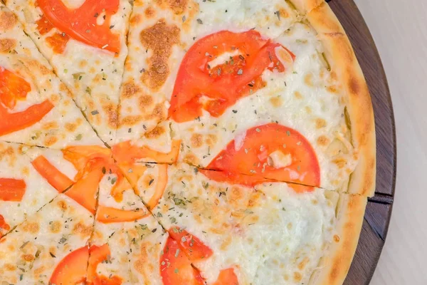 Die Hälfte der Pizza mit Tomaten und Käse auf Holzbrett schneiden. Ansicht von oben. — Stockfoto