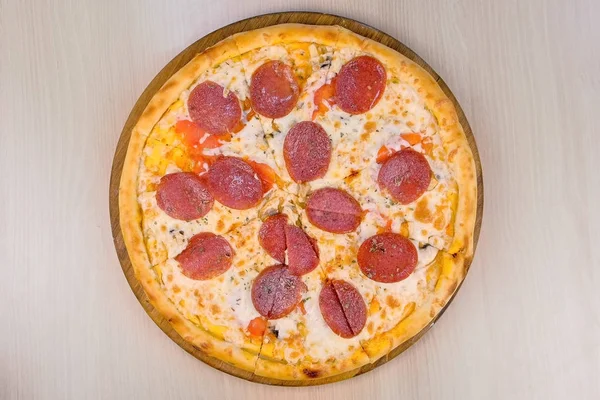 Szalámis pizza fából készült táblán az asztalon. Közeli kép: felülnézet. — Stock Fotó