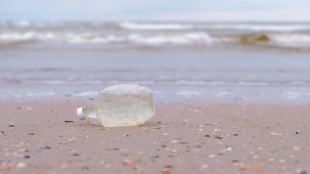 Plastová láhev byl přinesen k pobřeží na písčitém břehu. — Stock video