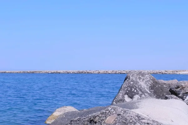 Tło Seascape z morzem kamień plaży i molo w zatoce w słoneczny dzień. — Zdjęcie stockowe