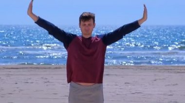 Adam yoga antrenmanı öncesi sahilde ısınıyor.