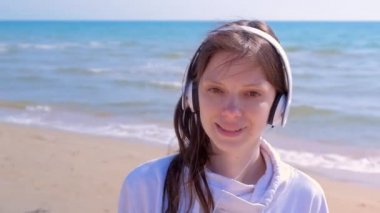 Portre mutlu kız yürür kulaklık müzik dinlemek baş deniz kum plaj sallar.