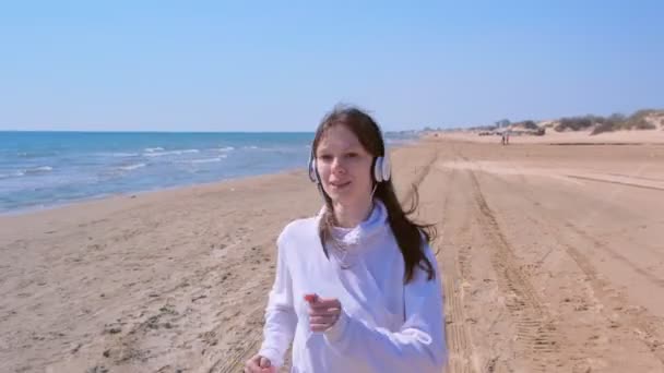 Ragazza che fa jogging in cuffia ascolta musica smettere di correre per prendere respiro sport all'aperto . — Video Stock