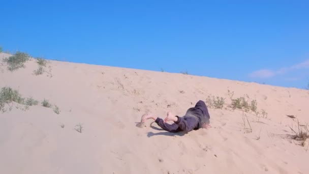 Enfant garçon ludique roule et culbute sur la plage de dunes de sable en vacances . — Video
