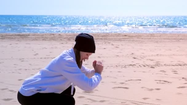 Дівчина присідає на морському піщаному пляжі фітнес на відкритому повітрі спортивні вправи на тренуваннях . — стокове відео