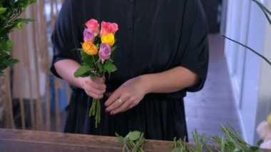 Kadın çiçekçi çiçek dükkanında renkli gül bir buket yapar, eller çekim.