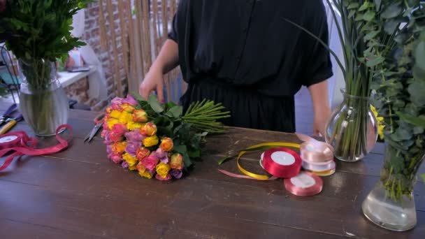 Florista mulher trabalha faz buquê de rosas coloridas na loja, mãos closeup . — Vídeo de Stock